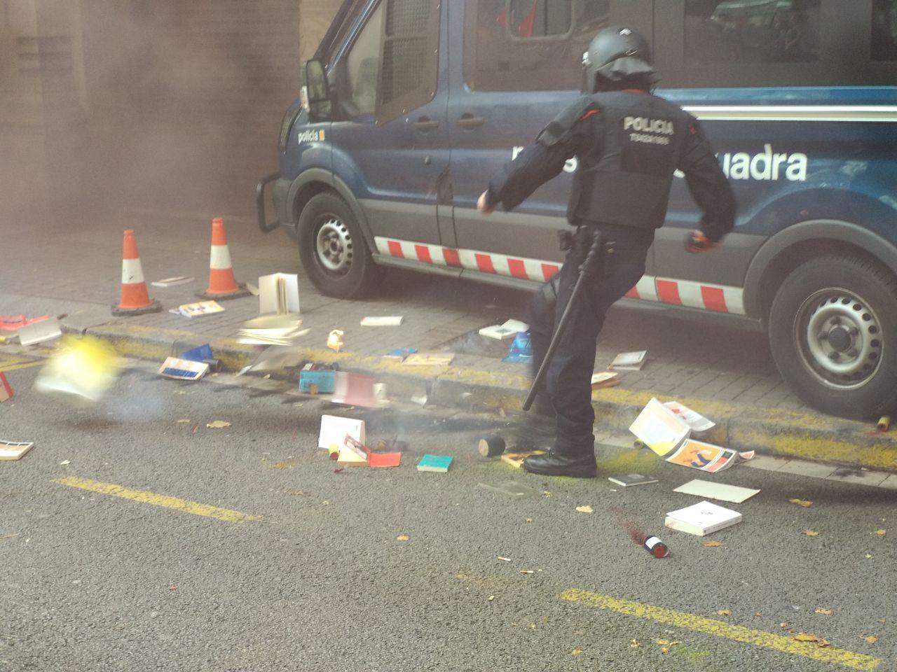 Un mosso intenta apagar un llibre encés llençat per un grup d'estudiants foto: Tomeu Ferrer