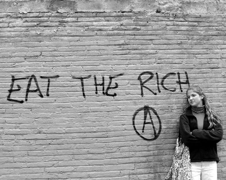 grafit eat the rich en un mur urbà com a símbol de desigualtat econòmica i crítica al poder